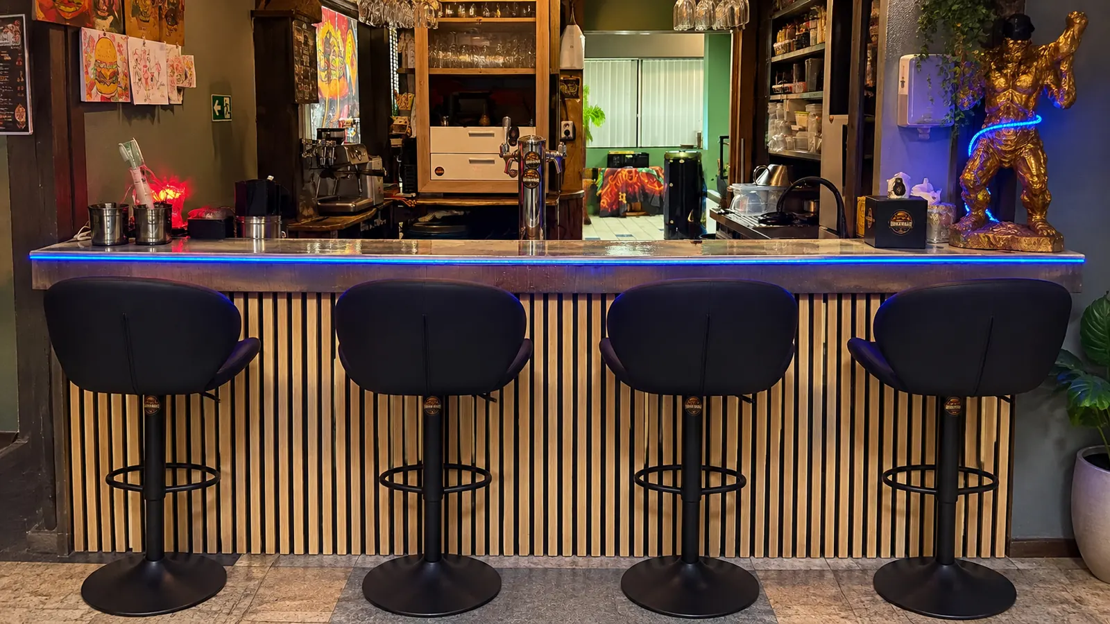 Die Theke der Burgerbar mit vier Barhockern, Pflanzen und blauem LED-Licht