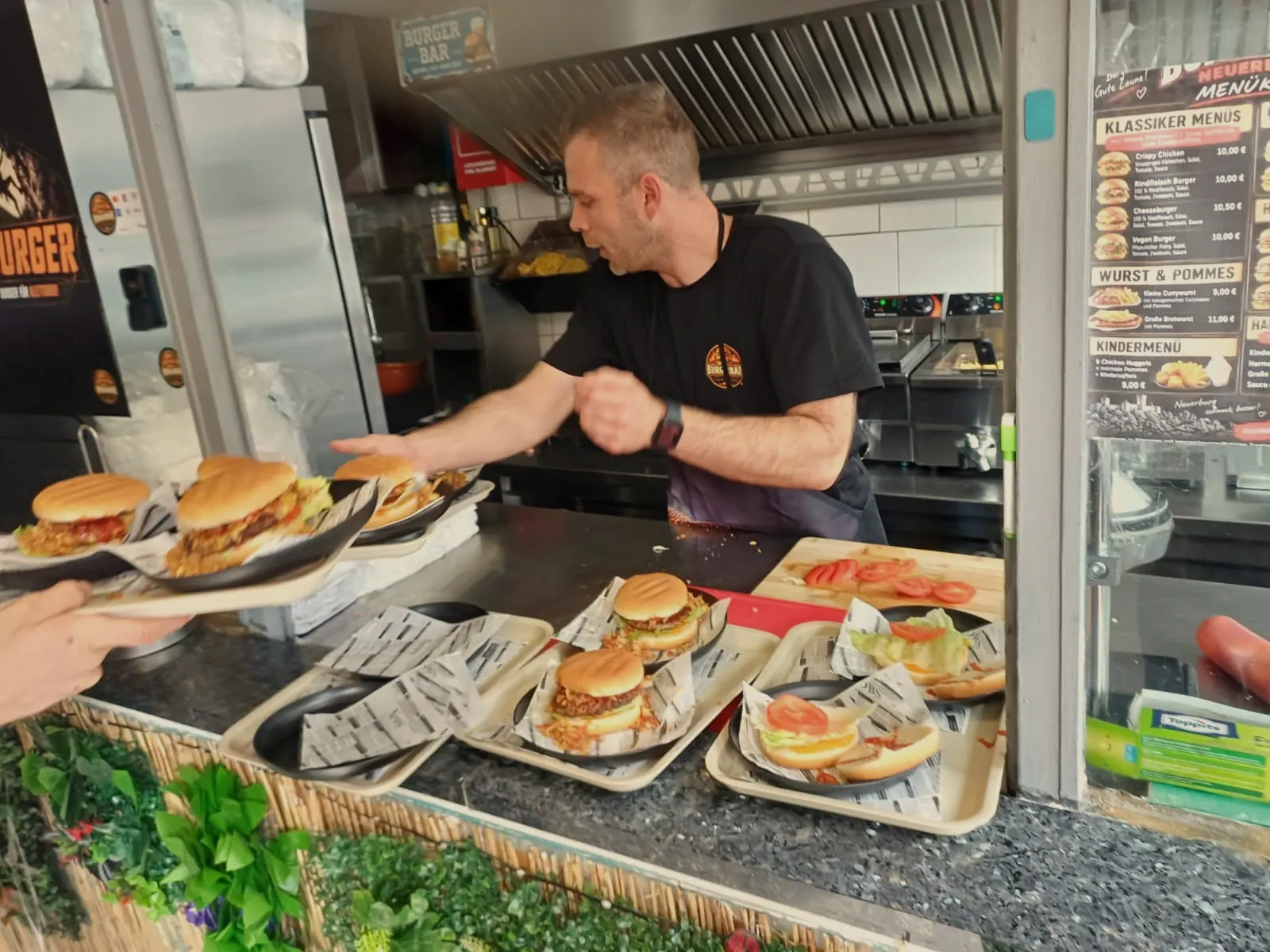Mike reicht die fertigen Burger über den Pass